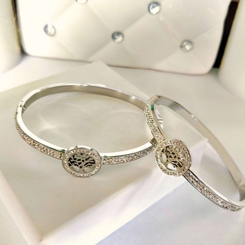 Srebrna, sztywna bransoletka typu bangle ze stali chirurgicznej, zaprezentowana na eleganckim tle. W centrum obręczy znajduje się okrągły motyw z Drzewem Życia, a część główna obręczy bogato wysadzana jest rzędami drobnych, lśniących cyrkonii.