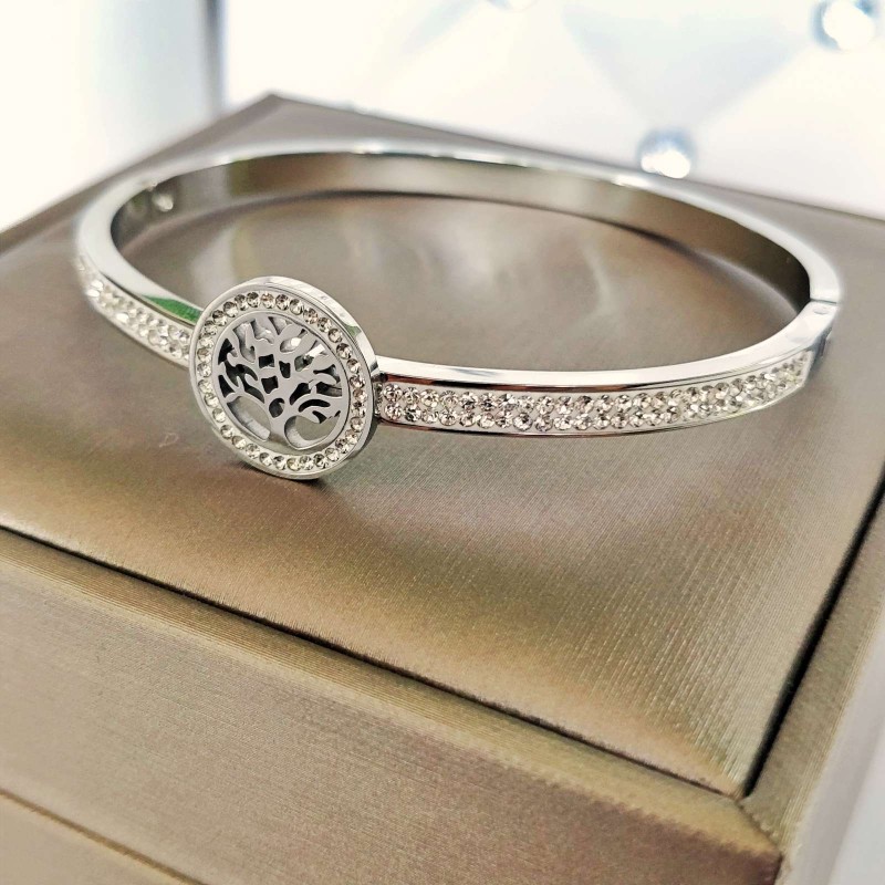 Srebrna, sztywna bransoletka typu bangle ze stali chirurgicznej, zaprezentowana na eleganckim tle. W centrum obręczy znajduje się okrągły motyw z Drzewem Życia, a część główna obręczy bogato wysadzana jest rzędami drobnych, lśniących cyrkonii.
