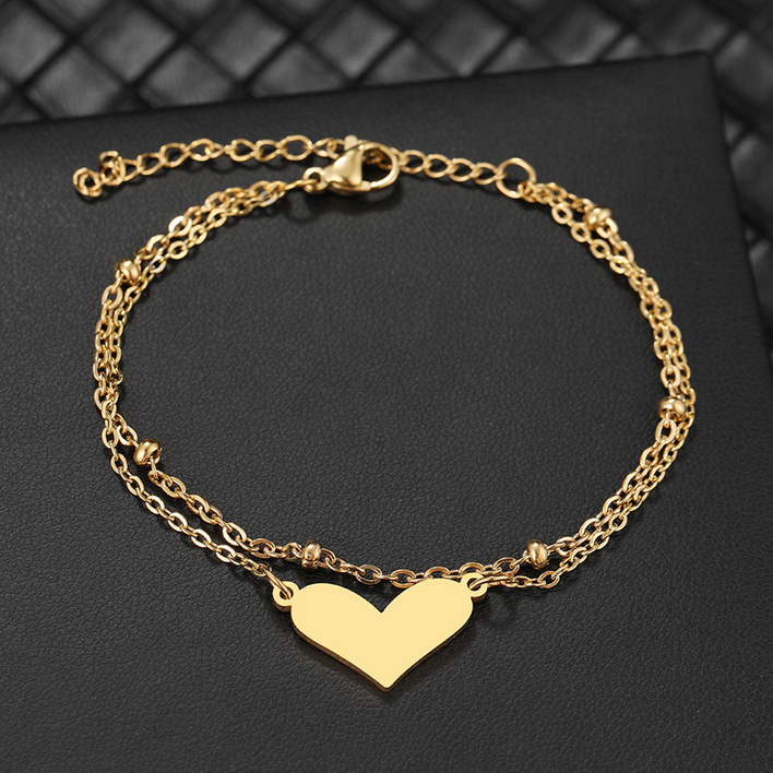 Złota, podwójna bransoletka ze stali chirurgicznej. Składa się z dwóch łańcuszków: jeden posiada ułożone poziomo, płaskie serduszko, drugi ozdobiony jest w regularnych odstępach drobnymi, gładkimi kuleczkami.