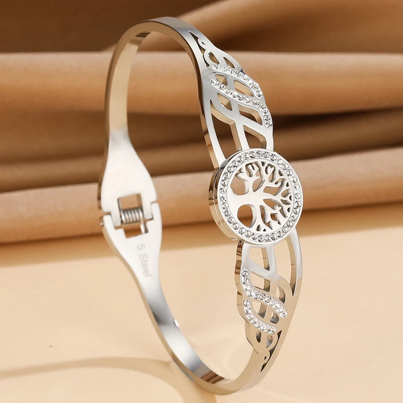 Sztywna bransoletka typu bangle ze stali chirurgicznej. W centrum obręczy znajduje się Drzewko Szczęścia otoczone cyrkoniami. Boki posiadają ażurowe wycięcia również wysadzane błyszczącymi kamieniami.