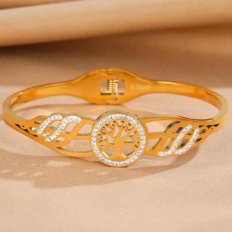 Sztywna bransoletka typu bangle ze stali chirurgicznej. W centrum obręczy znajduje się Drzewko Szczęścia otoczone cyrkoniami. Boki posiadają ażurowe wycięcia również wysadzane błyszczącymi kamieniami.