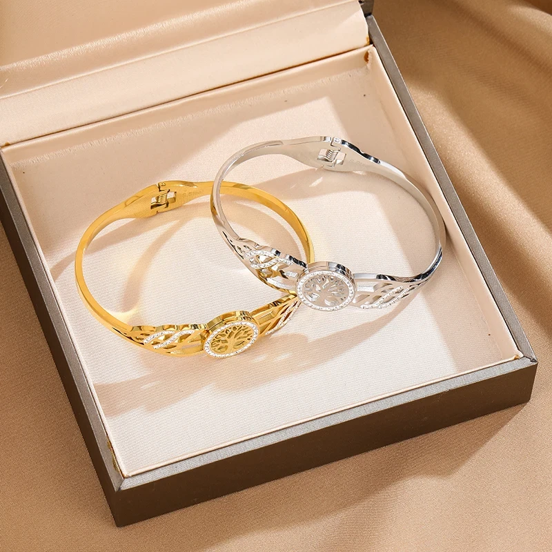 Sztywna bransoletka typu bangle ze stali chirurgicznej. W centrum obręczy znajduje się Drzewko Szczęścia otoczone cyrkoniami. Boki posiadają ażurowe wycięcia również wysadzane błyszczącymi kamieniami.