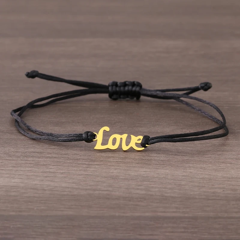 Minimalistyczna bransoletka z ciemnego sznurka jubilerskiego. W jej centralnym punkcie znajduje się gładka, złota zawieszka ze stali chirurgicznej w kształcie romantycznego, kaligrafowanego napisu Love.