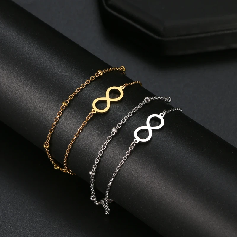 Złota bransoletka ze stali chirurgicznej na podwójnym łańcuszku z centralnym elementem w kształcie znaku nieskończoności.