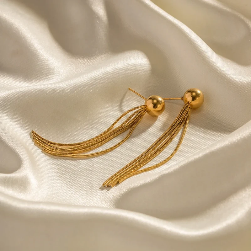 Długie złote kolczyki wiszące ze stali chirurgicznej (6 cm) składające się z gładkiej kuli przy uchu oraz kaskady cienkich łańcuszków typu żmijka.