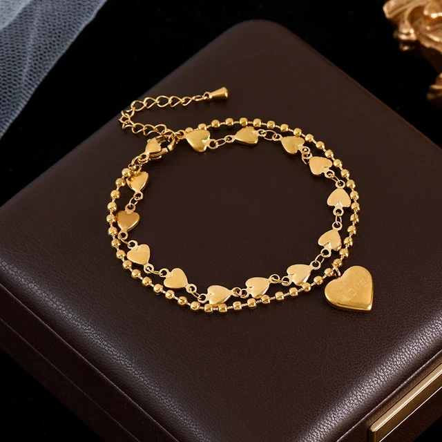 Złota podwójna bransoletka ze stali chirurgicznej składająca się z łańcuszka kuleczkowego oraz łańcuszka z serduszkami, z zawieszką w kształcie serca z napisem LOVE.