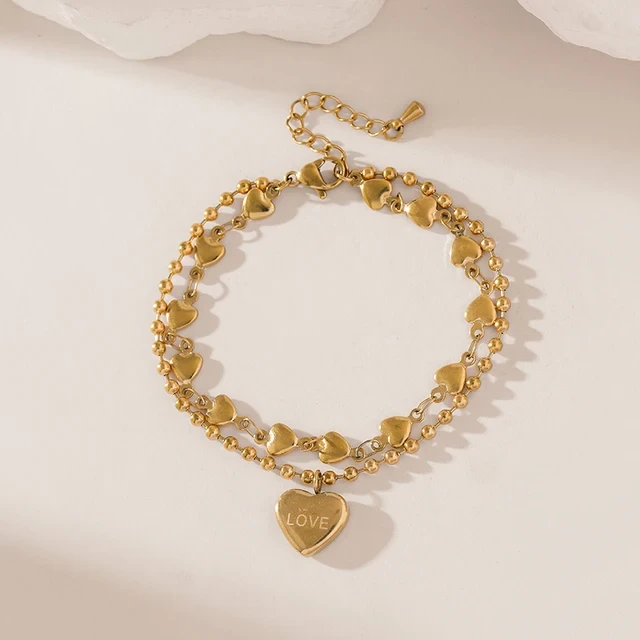 Złota podwójna bransoletka ze stali chirurgicznej składająca się z łańcuszka kuleczkowego oraz łańcuszka z serduszkami, z zawieszką w kształcie serca z napisem LOVE.