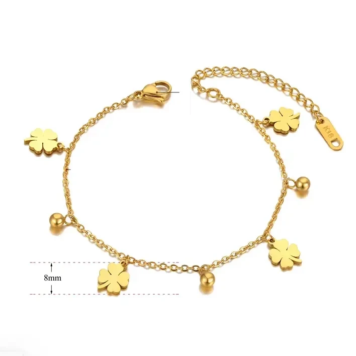 Delikatna, złota bransoletka łańcuszkowa ze stali chirurgicznej, ozdobiona naprzemiennie płaskimi zawieszkami w kształcie czterolistnych koniczynek oraz małymi kuleczkami.