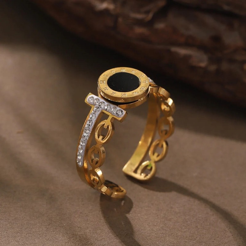 Złoty pierścionek regulowany ze stali chirurgicznej z motywem zegara, rzymskimi cyframi wokół czarnego środka i zdobieniem z cyrkonii.