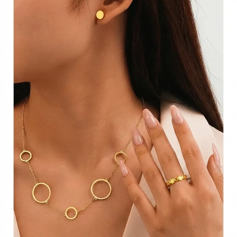 Złoty komplet biżuterii 3w1 ze stali chirurgicznej: naszyjnik z obręczami, kolczyki pełne kółka na sztyfcie oraz ażurowy pierścionek.