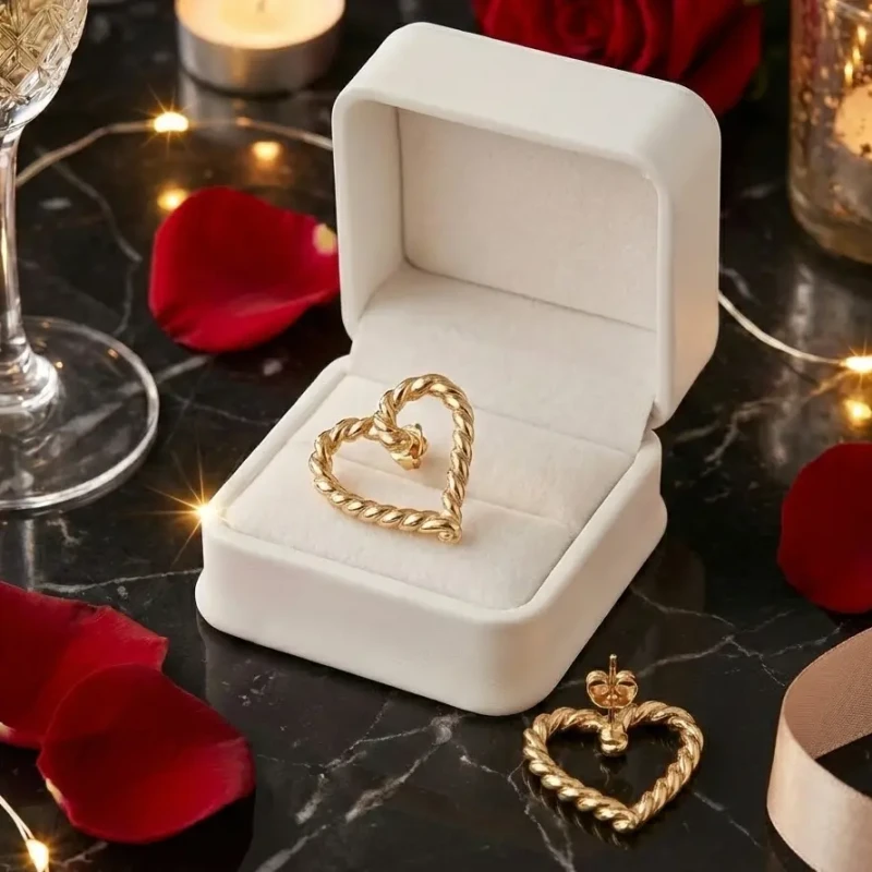 Złote kolczyki na sztyfcie w kształcie otwartego serca o fakturze skręconego sznura, wykonane ze stali chirurgicznej.