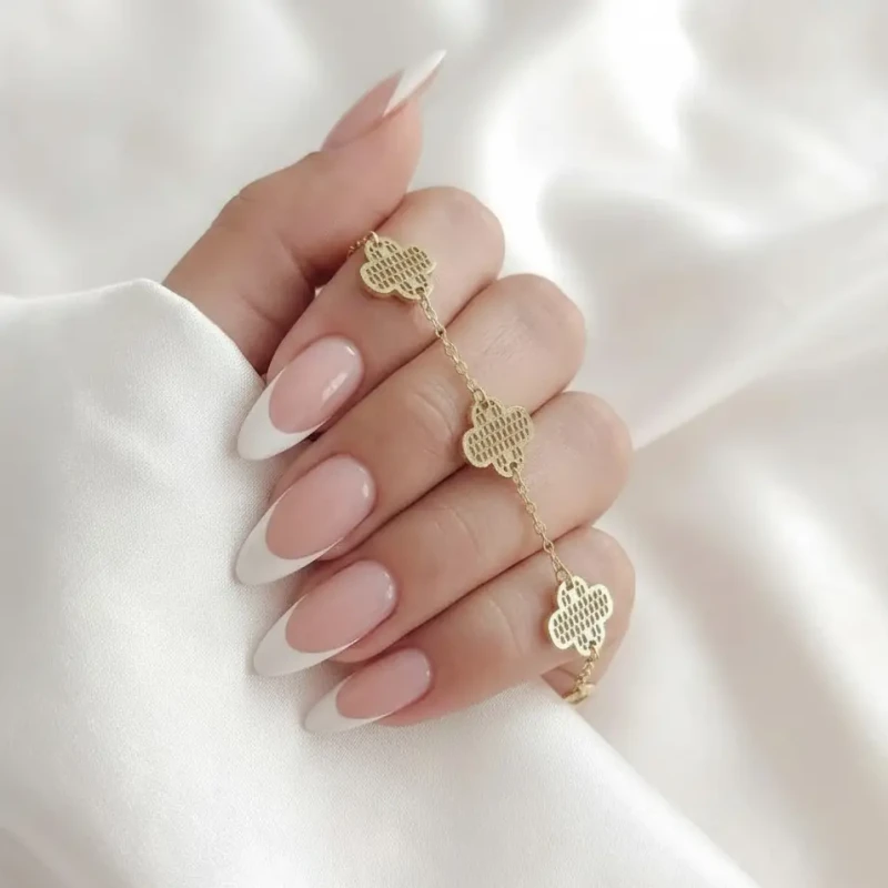 Złota bransoletka na rękę ze stali chirurgicznej z trzema zawieszkami w kształcie koniczyny o ozdobnej, kratkowanej fakturze.