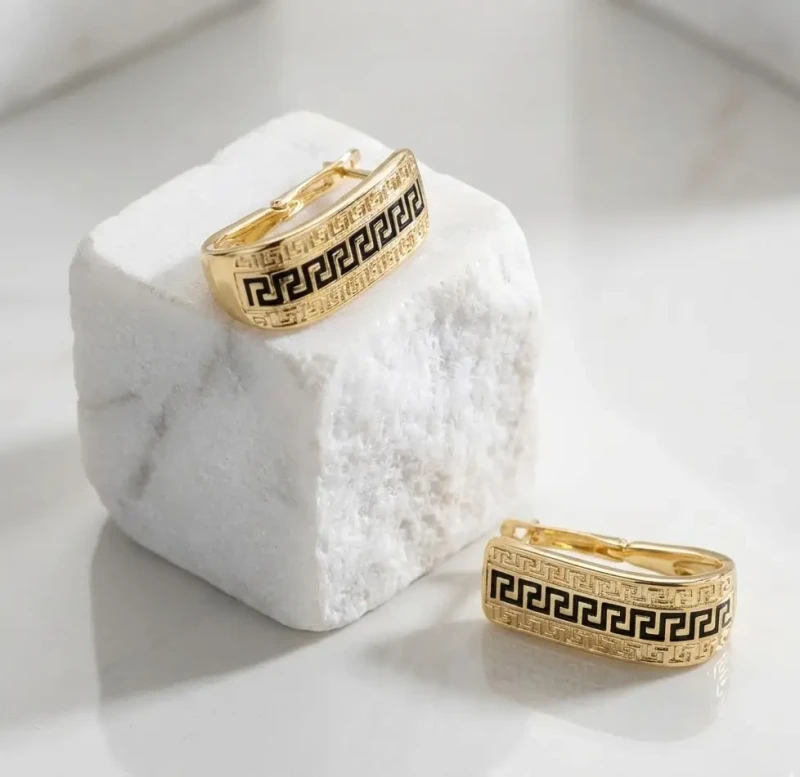 Złote prostokątne kolczyki ze stali chirurgicznej z czarnym wzorem greckim (meandrem) na wygodnym zapięciu zatrzaskowym.