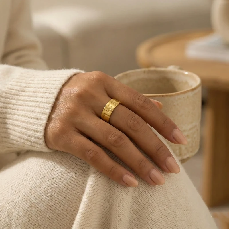 Złoty szeroki pierścionek regulowany ze stali chirurgicznej z tłoczonym wzorem greckim (meander) na obwodziee.webp