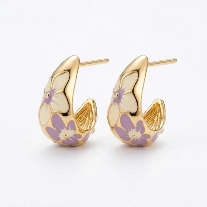 Złote kolczyki o kształcie szerokich półkoli na sztyfcie. Wykonane ze stali chirurgicznej, zdobione jasną emalią z malowniczym motywem kremowych i liliowych kwiatów.