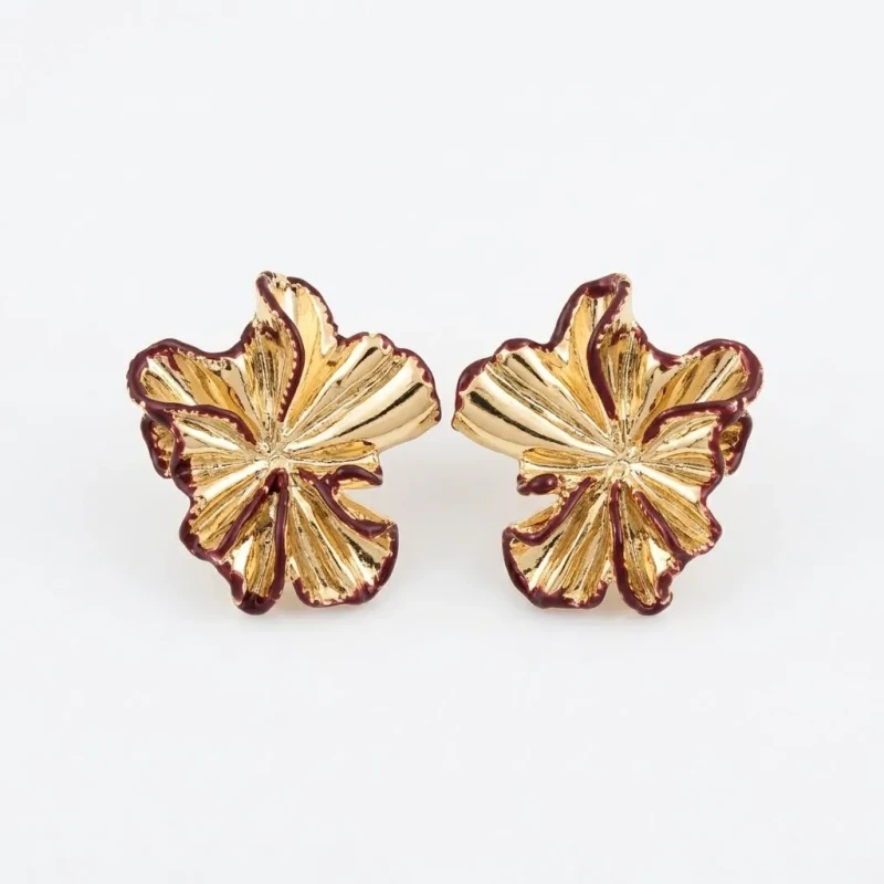 Złote kolczyki na sztyfcie w kształcie przestrzennych, pofalowanych kwiatów. Krawędzie rozłożystych płatków wykończone są cienką, bordową emalią.