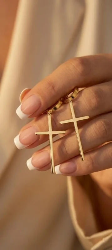 Długie, złote kolczyki wiszące ze stali chirurgicznej. Składają się z małego kółeczka z zapięciem zatrzaskowym, do którego doczepiony jest gładki, podłużny krzyżyk.